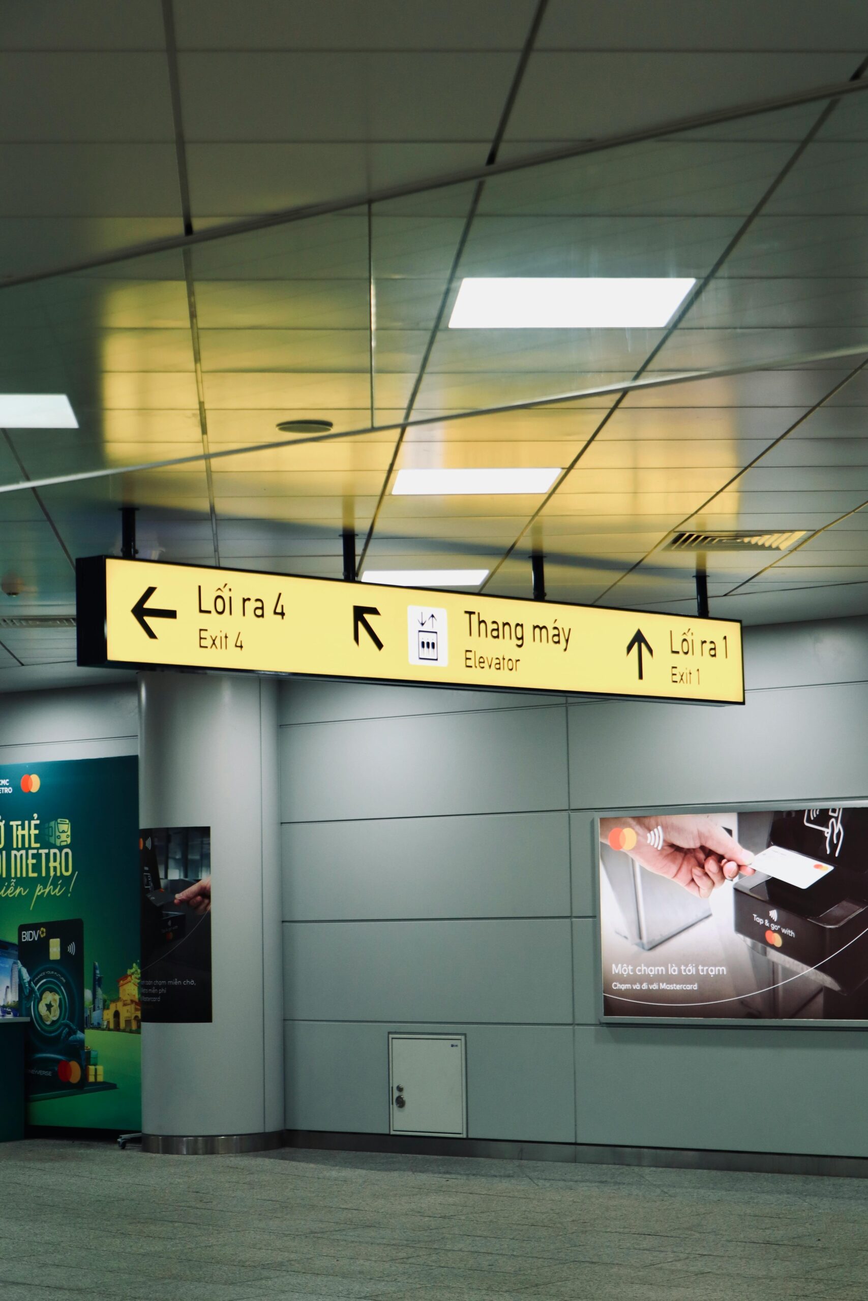 Indoor view of directional signs for exits and elevator in a Vietnamese airport.